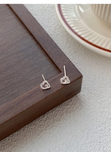 Gros plan de boucles d'oreilles nuages en argent S999 sur un plateau en bois