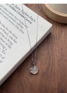 Dettaglio della collana in argento S999 con pendente in calcedonio bianco su un libro