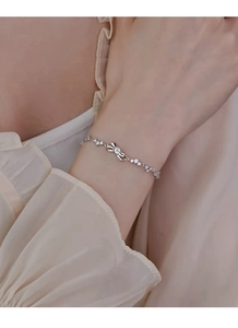 Detailed close-up of a silver bow bracelet with sparkling crystals on a woman's wrist