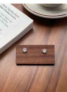 Detailed view of silver snowflake stud earrings with sparkling cubic zirconia on wood