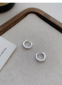 Détail de créoles en argent sterling S999 avec finition mate brossée sur surface en bois