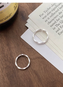 Detail of Mobius strip silver rings with matte brushed finish on a rustic wooden background