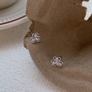 Elegant S999 silver clover stud earrings with sparkling zircons on vintage paper