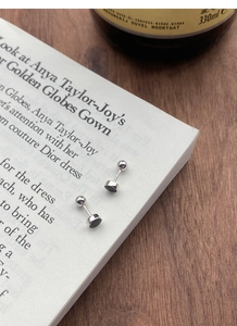 Détail de boucles d'oreilles rondes noires en argent S925 avec fermoir à vis sur un livre