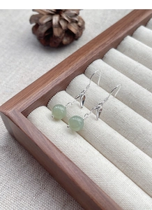 Detail view of S925 silver bamboo leaf earrings with green Hetian jade beads in a wooden box
