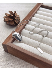 Close-up of polished S925 sterling silver oval pendant on a soft beige jewelry tray