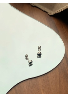 Gros plan de boucles d'oreilles à vis en argent S999 sur un socle miroir réfléchissant