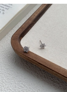 Macro shot of silver snowflake earrings with sparkling cubic zirconia on fabric display