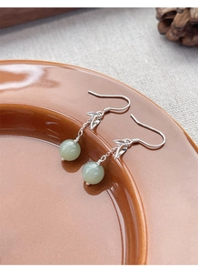 Detailed close-up of S925 silver bamboo leaf earrings with green jade beads on ceramic tray