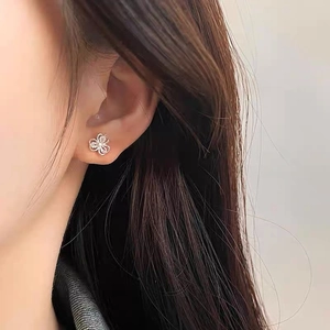 Elegant S999 silver four-leaf flower stud earrings with sparkling diamonds on a model
