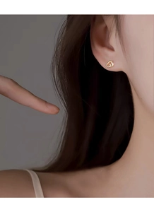 Gros plan d'élégantes boucles d'oreilles cœur creux en or au style minimaliste