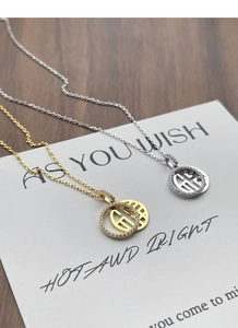 Gros plan de colliers pendentifs Fu en argent sterling S925 avec finitions or et argent