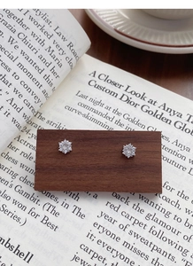 Detailed view of sparkling S999 silver snowflake earrings displayed on a dark wooden card