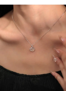 Dettaglio della collana in argento S999 con pendente tondo in calcedonio bianco sul collo