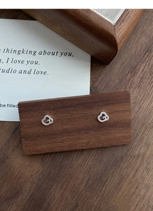 Détail de petites boucles d'oreilles clous en argent S999 motif nuage sur bois