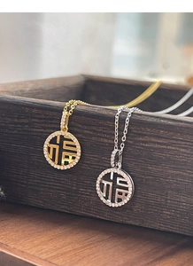 Détail de pendentifs Fu en argent et or avec des accents scintillants en zircone