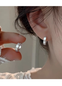 Gros plan de créoles en argent sterling S999 avec une finition mate brossée sur le lobe