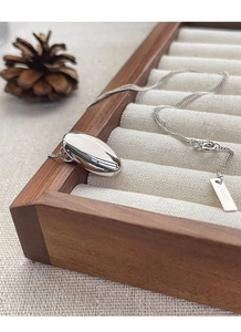 Detail view of polished S925 sterling silver oval pendant and hallmark on fine chain