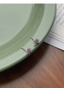 Macro detail of silver snowflake stud earrings with sparkling cubic zirconia on ceramic