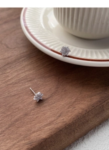 Macro shot of silver snowflake earrings with cubic zirconia on wood and ceramic