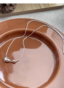 Elegant S925 sterling silver heart necklace on a ceramic plate with warm rustic decor