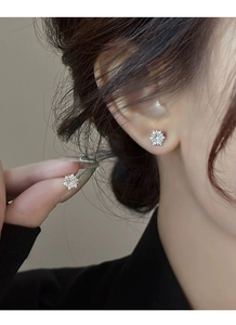 Macro shot of silver snowflake stud earrings with sparkling cubic zirconia on an earlobe