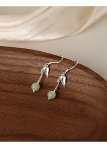 Detail view of silver bamboo leaf earrings with Nephrite Jade beads on silk fabric