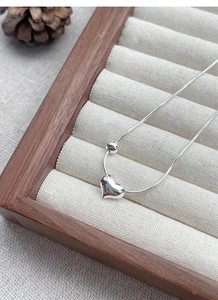 Macro shot of polished S925 sterling silver heart pendant on a fine snake chain necklace