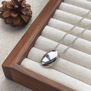 Minimalist S925 sterling silver oval pendant necklace on a wooden jewelry display tray