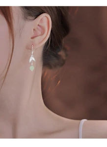 Detail of silver bamboo leaf earrings with green jade beads on a model's ear