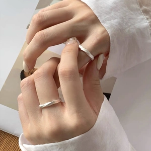 Minimalist S999 silver Mobius rings with matte finish worn by models on a wooden table