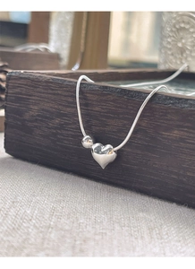 Detail of S925 sterling silver snake chain necklace with polished heart and bead charms
