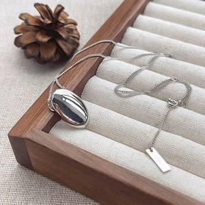Minimalist S925 sterling silver oval bean pendant necklace on a textured jewelry tray