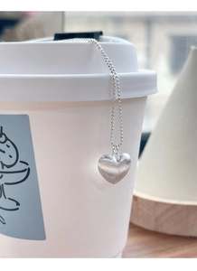 Dettaglio della collana cuore in argento S925 con finitura opaca spazzolata su una tazza