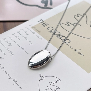 Minimalist S925 sterling silver oval pendant necklace on artistic paper backdrop