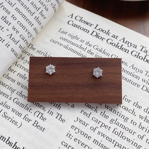 Sparkling S999 sterling silver snowflake stud earrings displayed on a wooden stand