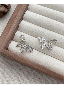 Detailed macro view of S925 sterling silver butterfly studs with gold floral accents