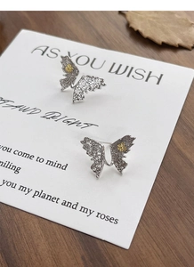 Close-up of S925 silver butterfly earrings with hollow pattern and gold flower detail