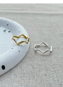 Detail of minimalist wavy silver and gold open rings on an elegant jewelry tray