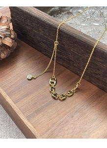 Makro-Detail einer goldenen Schweinenase-Gliederkette mit Zirkonia-Anhänger auf Leinen