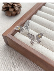 Macro shot of S925 silver butterfly studs with hollow patterns and gold floral accents