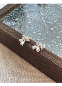 Detail of silver lily of the valley bow earrings on a vintage textured background