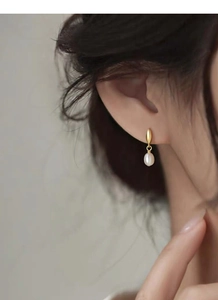 Détail de boucles d'oreilles feuille d'or en argent S925 avec perles d'eau douce sur modèle