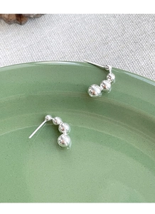 Detail of S925 sterling silver geometric bead earrings on a green ceramic plate