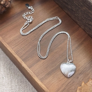 Ciondolo a cuore in argento S925 spazzolato con catena a sfere su vassoio di legno rustico