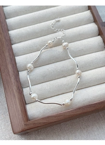 Detail view of the S925 sterling silver wavy bar bracelet with white freshwater pearls