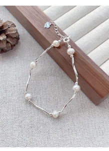 Macro view of S925 sterling silver curved tube bracelet with freshwater pearls and heart tag
