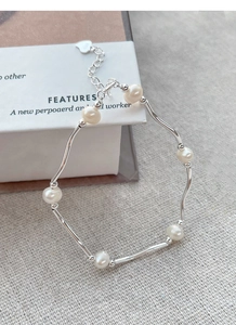 Detail view of S925 sterling silver curved tube bracelet with freshwater pearls and heart tag