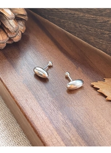 Close-up of polished S925 silver oval stud earrings with screw back on wooden tray