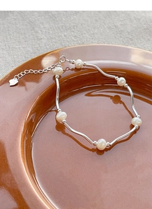 Detailed macro view of S925 silver wave links with freshwater pearls and a heart charm